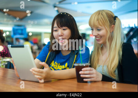 Zwei junge Frauen, die mit digital-Tablette in einem café Stockfoto
