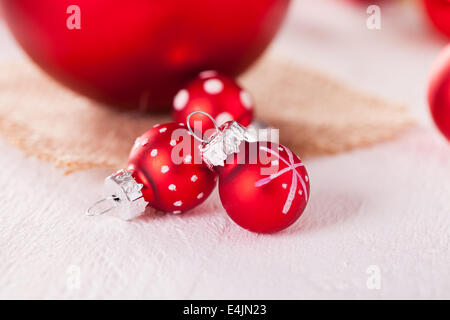 Hübsche rote Polka Dot Weihnachtskugel in einem rustikalen Xmas saisonalen Hintergrund mit Sackleinen und vereinzelte rote Kugel Dekorationen mit f Stockfoto