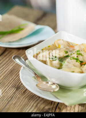 Schüssel mit herzhaften Tortellini Nudeln gefüllt mit Schweinefleisch in eine schmackhafte Brühe mit frischen Kräutern gewürzt und zum Abendessen serviert Stockfoto