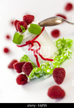 Frische reife Himbeeren serviert mit einem Glas des gesunden Joghurt oder Clotted Cream für ein leckeres Dessert oder Frühstück mit copysp Stockfoto