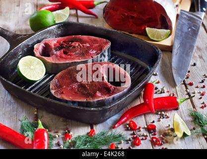 Frischen rohen Thunfisch Tail auf Holzbrett mit red hot Chili peppers, frische Limette und Dill. Selektiven Fokus. Stockfoto