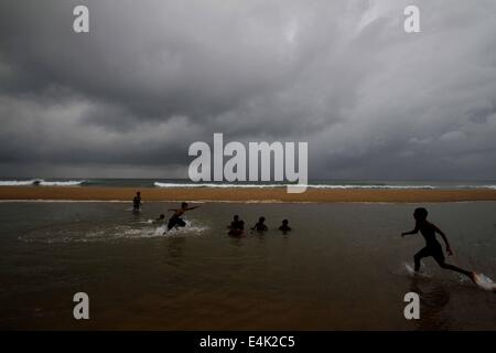 Puri, indischen Bundesstaat Orissa Hauptstadt Bhubaneswar. 13. Juli 2014. Lokalen Jungen spielen im Regen als Monsun Wolken schweben über den Himmel über dem Golf von Bengalen Meer Ostküste Strand bei Puri, 65 km von der östlichen indischen Bundesstaat Orissa Hauptstadt Bhubaneswar, 13. Juli 2014. © Stringer/Xinhua/Alamy Live-Nachrichten Stockfoto