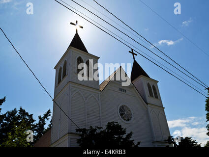 Sonnenstrahlen glühende hinter der ein Kreuz auf die Heiligen Herzen katholische Kirche in La Conner, Washington. Historische Kathedrale Gegenlicht Stockfoto