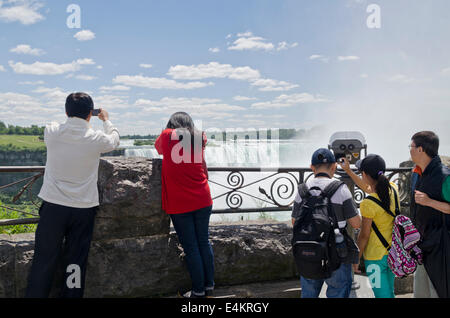 Eine Familie asiatischer Touristen, die die Niagarafälle an einem sonnigen Sommertag von der kanadischen Seite aus beobachten und fotografieren. Stockfoto