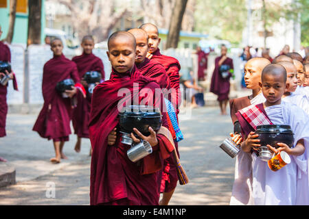 Buddhistische Mönche und Nonnen warten für Lebensmittel im Rahmen einer Almosen Zeremonie im Maha Aung Mye Bonzan Kloster in Mandalay, Myanmar. Stockfoto