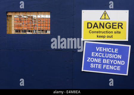 Zaun um eine Baustelle mit einem Ausschnitt-Fenster erlaubt Menschen zu durchschauen und Warnzeichen Stockfoto