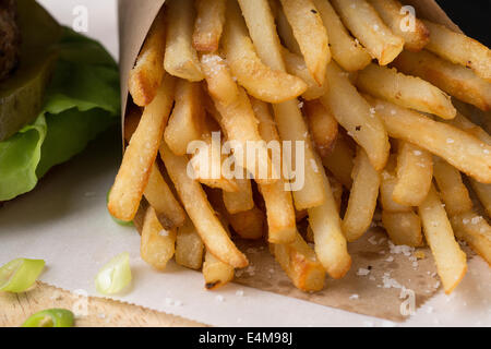 Pommes frites hautnah mit Gurke & Salat Detail von Burger. Stockfoto