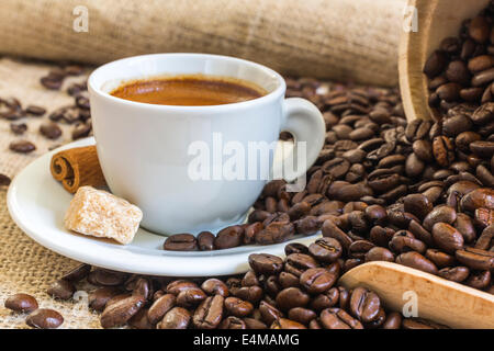 frischer Espresso Kaffee in weiße Tasse mit Würfelzucker, Zimt und gerösteten Kaffeebohnen Stockfoto