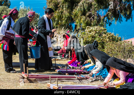 Puno, Peru - 25. Juli 2013: Priester Segen Frauen beim Weben in den peruanischen Anden auf Taquile Island auf Puno Peru am 25. Juli 2013. Stockfoto