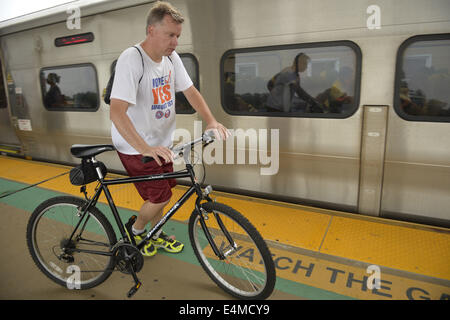 Merrick, New York, USA. 14. Juli 2014. Während der AbendHauptverkehrszeit geht ein Mann mit seinem Fahrrad auf erhöhten Plattform zum Board Zug am Bahnhof Merrick der Filiale in Babylon, nach MTA Metropolitan Transit Authority und Long Island Rail Road Union spricht Deadlock mit Potenzial LIRR schlagen sich abzeichnende nur wenige Tage vor. © Ann Parry/ZUMA Draht/Alamy Live-Nachrichten Stockfoto