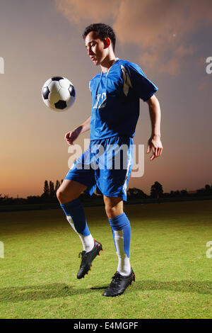 Football-Spieler in einer blauen Uniform Kugel anheben Stockfoto