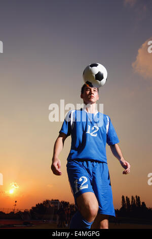 Football-Spieler in einer blauen Uniform Kugel anheben Stockfoto