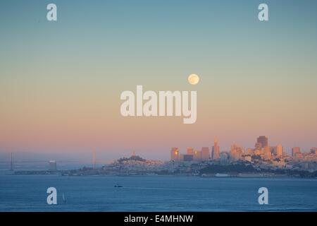 Die wunderschöne Skyline von San Francisco in der Dämmerung mit einem Vollmond über Bergen Stockfoto