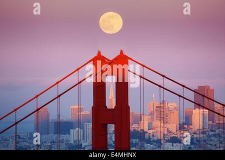 Der Vollmond steigt über die Golden Gate Bridge und die Skyline von San Francisco. Stockfoto