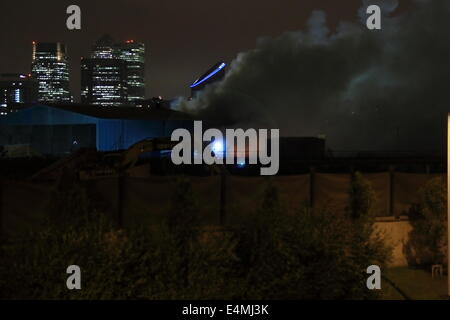 London, UK. 15. Juli 2014. Einige 70 Feuerwehrleute aus ganz London aufgerufen, um ein Feuer in einem Abfallzwischenlager auf enge Skarabäus, Canning Town East London zu bewältigen. Crews aus so weit weg wie Tooting hießen die Szene auf der Glut eingehen, die mehrere hundert Tonnen Reststoffen beteiligt. Dicker Rauch bauschte aus das Feuer führte zu LFB Warnung Anwohner, Türen und Fenster geschlossen zu halten. Es ist noch nicht bekannt, wenn die Schließung der von Silvertown Feuerwache erbittert Blaze schließen, da Besatzungen mussten aus weiter zu dem Vorfall zu reisen. Bildnachweis: HOT SHOTS/Alamy Li Stockfoto