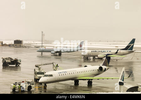 Vor dem Start vom Flughafen Calgary während eines Schneesturms Flugzeuge Auftausalz. Stockfoto