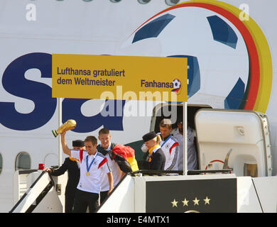 Berlin, Deutschland. 15. Juli 2014. Deutschlands Philipp Lahm (C), gefolgt von seinem Teamkollegen Bastian Schweinsteiger und Thomas Mueller (R), Schritt aus dem Flugzeug hält den WM-Pokal in seinen Händen als Deutschlands Fußball Mannschaft am Flughafen Tegel in Berlin, Deutschland, 15. Juli 2014 kommt. Team Deutschland gewann Brasilien 2014 FIFA Soccer World Cup-Finale gegen Argentinien mit 1: 0, den Weltmeister-Titel zum vierten Mal nach 1954, 1974 und 1990 Weltmeisterschaften. Foto: JENS Büttner/Dpa/Alamy Live News Stockfoto