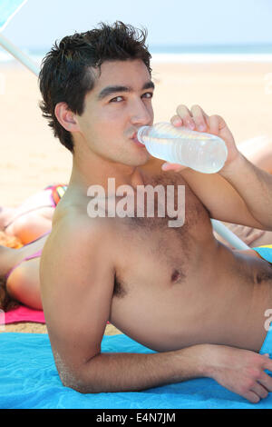 Teenager Trinkwasser am Strand Stockfoto