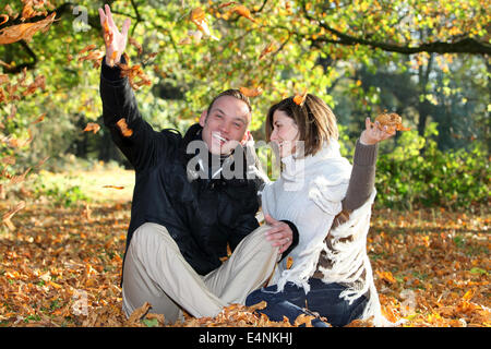 Glückliches Paar spielen mit Herbstlaub Stockfoto