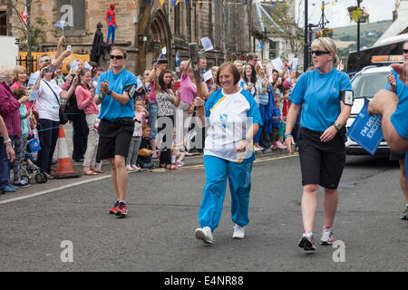 Ayrshire, Schottland, Vereinigtes Königreich. 15. Juli 2014. Frau Betty Wilson trägt den Stab durch die Stadt Dalry in North Ayrshire, Schottland, während der Königin Baton Relay für den Glasgow2014 Commonwealth Games. Stockfoto