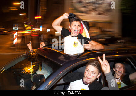 Wiesbaden, Deutschland. 14. Juli 2014. Deutschland gewinnt das FIFA WM 2014. Menschen in ihren Autos und auf der Straße, jubeln und feiern in der Innenstadt von Wiesbaden nach Deutschlands Sieg über Argentinien im Endspiel. Bewegung verwischt Auto und City Lights Credit: Oliver Kessler/Alamy Live News Stockfoto