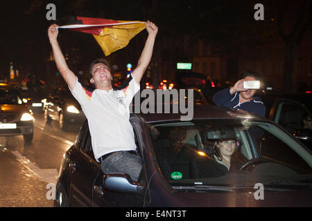 Wiesbaden, Deutschland. 14. Juli 2014. Deutschland gewinnt das FIFA WM 2014. Menschen in ihren Autos und auf der Straße, jubeln und feiern in der Innenstadt von Wiesbaden nach Deutschlands Sieg über Argentinien im Endspiel. Ein Mann mit einer deutschen Flagge hoch. Bewegungsunschärfe. Bildnachweis: Oliver Kessler/Alamy Live-Nachrichten Stockfoto