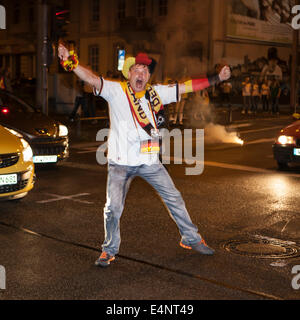 Wiesbaden, Deutschland 14. Juli 2014. Deutschland gewinnt das FIFA WM 2014. Menschen in ihren Autos und auf der Straße, jubeln und feiern in der Innenstadt von Wiesbaden nach Deutschlands Sieg über Argentinien im Endspiel. Ein Mann mit einer deutschen Flagge Tänze auf der Straße. Bewegungsunschärfe. Bildnachweis: Oliver Kessler/Alamy Live-Nachrichten Stockfoto