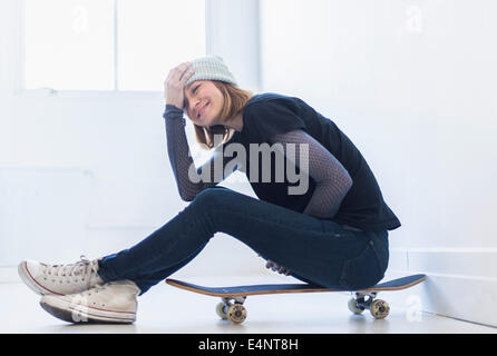 Junge Frau sitzt auf skateboard Stockfoto