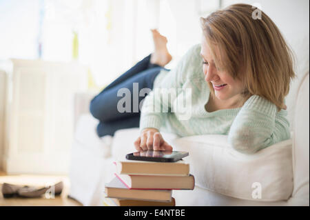 Frau auf dem Sofa liegend und mit digital-Tablette Stockfoto