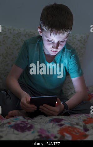 Jungen (8-9) mit digital-Tablette im Bett Stockfoto
