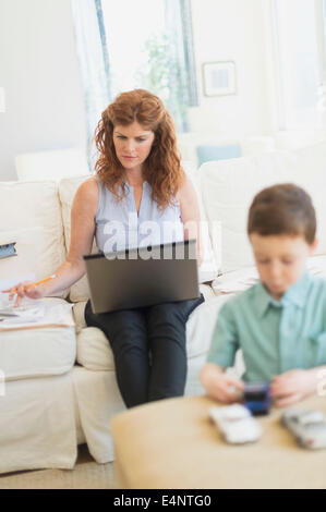 Mutter mit Laptop, Sohn (6-7) spielen mit Spielzeug-Autos Stockfoto