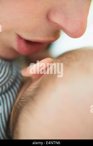 Nahaufnahme von Mutters Mund flüstern in Baby Boy (2-5 Monate) Ohr Stockfoto