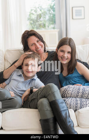 Mutter und Kinder (8-9, 10-11) sitzen auf dem sofa Stockfoto