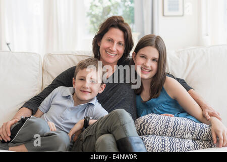 Mutter und Kinder (8-9, 10-11) sitzen auf dem sofa Stockfoto