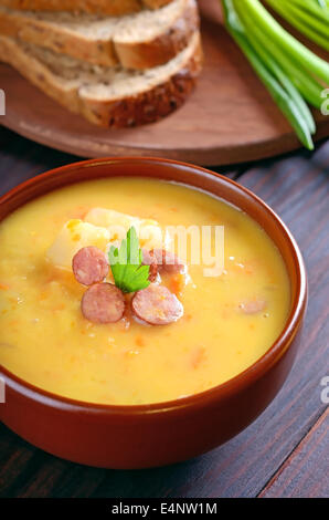 Erbsensuppe in Keramikschale auf Holztisch Stockfoto