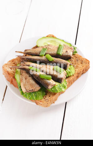 Sprotten Sandwich auf weißen Teller auf Holztisch Stockfoto