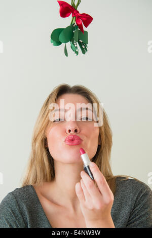 Junge Frau unter Mistel kräuseln Stockfoto