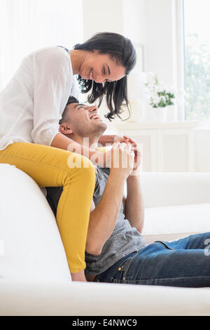 Glückliches junges Paar spielen auf sofa Stockfoto