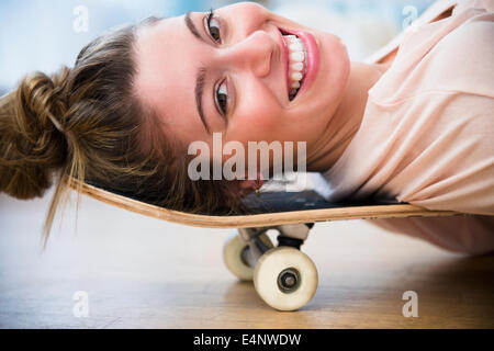 Porträt der jungen Frau liegend auf skateboard Stockfoto