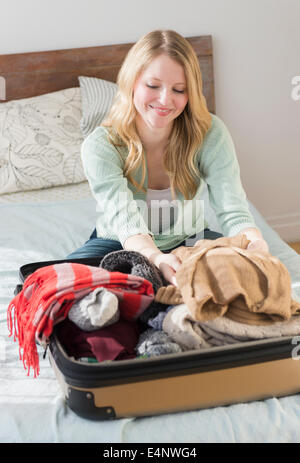 Frau am Bett sitzen und Koffer packen Stockfoto