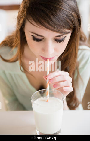 Junge Frau trinkt Milch mit Stroh Stockfoto