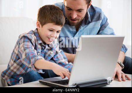 Vater arbeitet auf Laptop mit seinem Sohn (8-9) Stockfoto
