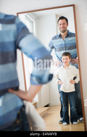 Vater und Sohn (8-9) Blick auf ihr Spiegelbild im Spiegel Stockfoto