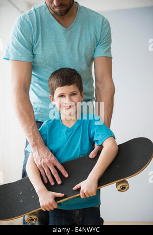 Skateboard-Vater und Sohn (8-9) halten Stockfoto