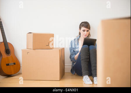 Junge Frau sitzt im Stock mit digital-Tablette mit Boxen um sie herum Stockfoto