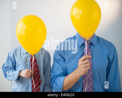 Vater und Sohn (8-9) gelbe Ballons halten Stockfoto