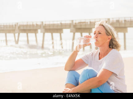 USA, Florida, Jupiter, Senior Woman Trinkwasser am Strand Stockfoto