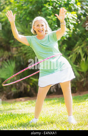 Porträt des senior Frau Spinning Hula-Hoop Stockfoto