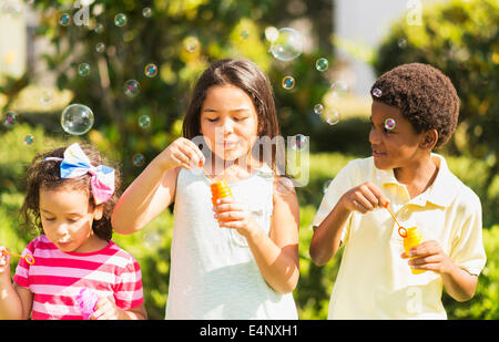 Mädchen (4-5, 8-9) und junge (6-7) bläst Seifenblasen Stockfoto