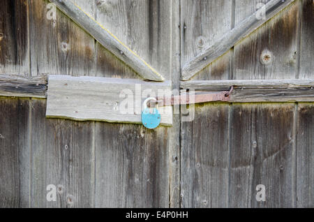 ländlichen Scheune Holztür mit eisenblau Schloss hängen Stockfoto